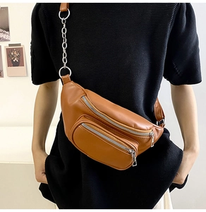 Detail showing the brown PU leather waist bag with silver chain strap and dual zippers