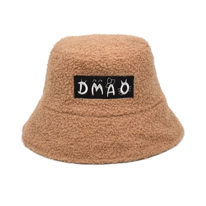Detail shot of caramel sherpa bucket hat featuring a black rectangular DMAO logo patch
