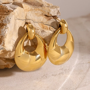 Détail macro de boucles d'oreilles dorées géométriques sur une pierre minérale naturelle