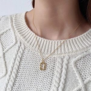 Close-up of a gold irregular textured rectangle pendant on a woman's neck