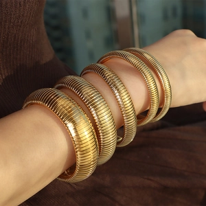 Stacked gold snake bone bracelets with textured metal finish on a female model arm