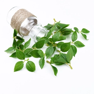 Artificial rose stems with green leaves and brown twine in a clear glass bottle
