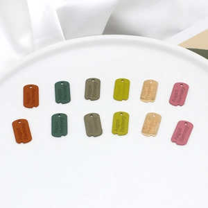 Close-up of Morandi colored alloy pendants with August Harmony engraving on a ceramic plate