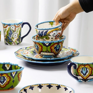 Hand-painted ceramic dinnerware set with colorful floral patterns and blue rims