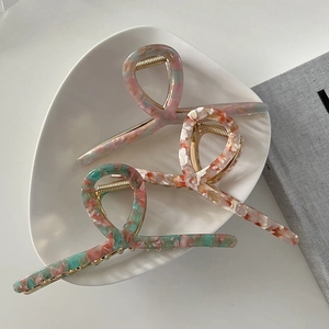 Three oversized 13cm marble acetate claw clips for thick hair on a white ceramic plate