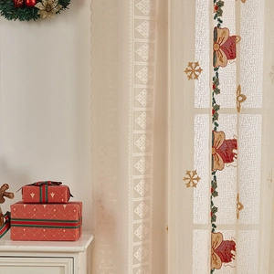Detail of beige Christmas lace curtain with red bow and gold snowflake embroidery