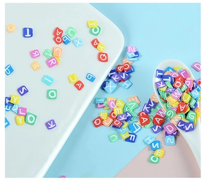 Close-up of colorful resin alphabet letter cubes in a white ceramic dish for DIY jewelry