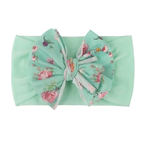 Détail du bandeau bébé en nylon côtelé vert menthe avec un grand nœud floral