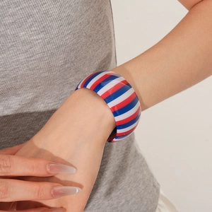 Detail shot of wide striped bangle with red white and blue pattern on female wrist