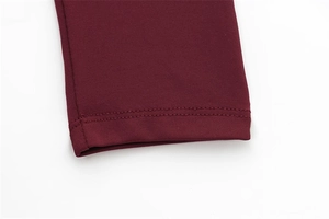 Detail of burgundy knitted dress showing precise double-needle stitching and fabric texture