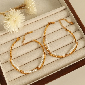 Double-layered 18K gold plated pearl bracelets with wavy metal design on jewelry tray