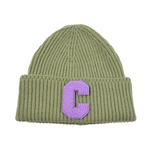 Detailed knit texture of green beanie with purple embroidered letter C patch on cuff