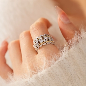 Close-up of hollow zircon lace open ring worn on finger with soft white sweater background