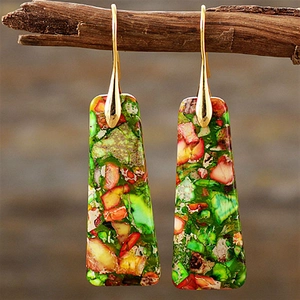 Detail of bohemian teardrop earrings with colorful stone inlay hanging on a wooden stand