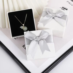White jewelry gift box with silver ribbon featuring a gold necklace with green jade pendant