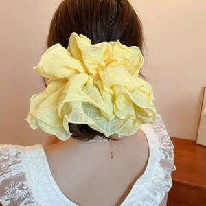 Close-up of fluffy light yellow ruffled fabric scrunchie worn on a hair bun
