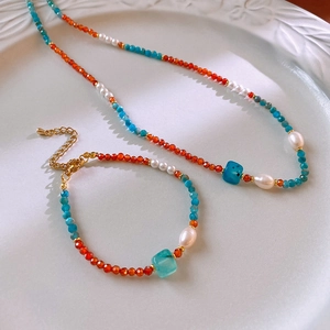 Detail of beaded necklace and bracelet with natural orange stones and freshwater pearls