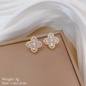Detailed macro view of gold-tone four-leaf clover earrings with sparkling cubic zirconia