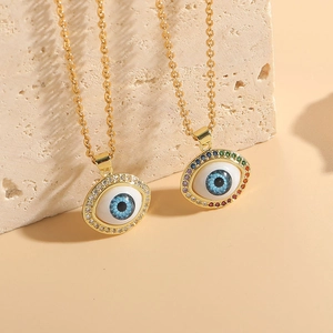 Macro shot of 14K gold-plated Evil Eye necklaces with colorful zircon stones on stone background