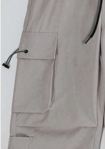 Detail of cargo flap pocket and adjustable drawstring on techwear parachute pants