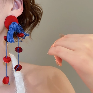 Detail view of bold red and blue long tassel earrings on a model with artistic design