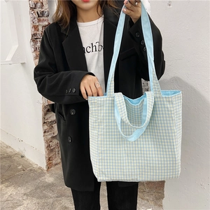 Bolso tote de lona a cuadros azules y beige mostrado por una modelo en exteriores