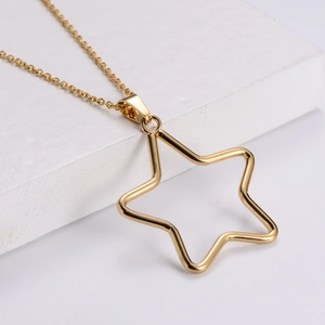 Minimalist gold stainless steel necklace with open star pendant on textured stone