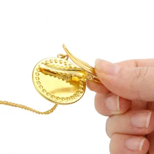 Golden pacifier clip with round pendant and fine chain featuring an alligator hair clip