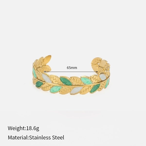 Detail of leaf pattern gold-plated stainless steel cuff with green and white enamel