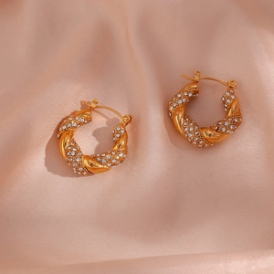 Close-up of gold twist hoop earrings with pavé crystals on elegant pink silk fabric