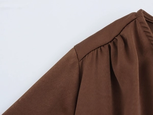 Close-up of brown chiffon dress shoulder featuring pleated sleeve and stitching details