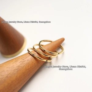 Macro detail of three 18K gold-plated minimalist rings with colorful gemstones on a stand