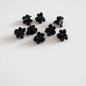 Gros plan de huit petites pinces à cheveux en forme de fleur noire brillante en résine