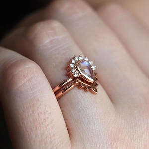 Close-up of rose gold pear-shaped moonstone ring set with sparkling side stones