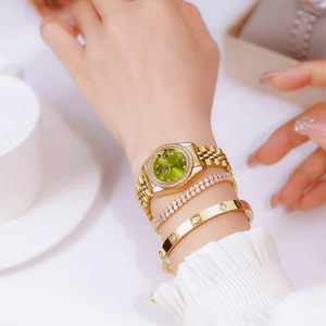 Close-up of gold women's watch with green dial and matching crystal bracelets on wrist