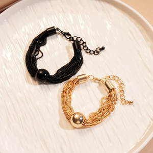 Detail view of multi-layered metal necklaces with central beads in black and gold finishes