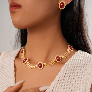 Détail d'une parure vintage dorée avec gemmes rouges ovales portée par un modèle