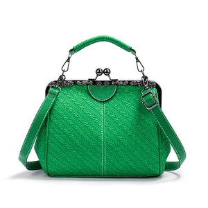 Detail of green woven texture and vintage metal kiss-lock frame on retro crossbody bag