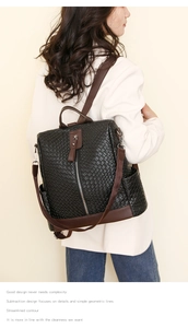 Detail of black woven texture backpack with brown leather handles on a female model
