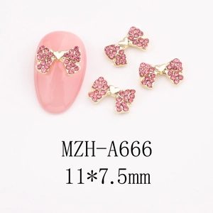 Detail view of 11x7.5mm bow-shaped pink rhinestone alloy charms on a soft pink nail