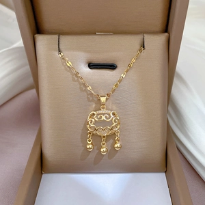 Detail of gold longevity lock pendant with small bells and faux jade on silk fabric