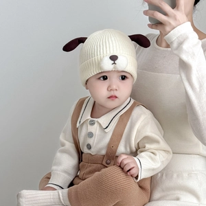 Close-up of baby winter knit set with puppy ear hat and beige jumper in a cozy studio setting
