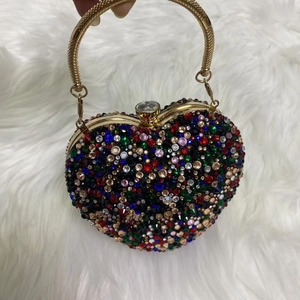 Close-up of heart-shaped evening bag with colorful rhinestones and metal handle