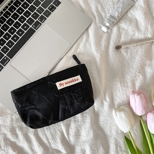 French embossed floral makeup bag with black bow and label on white sheets