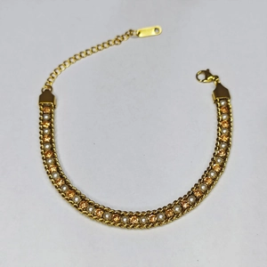 Detail of gold woven bracelet featuring amber faceted gems and white pearls on a white background