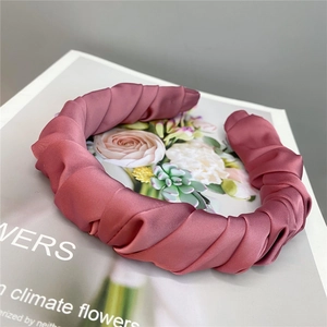 Detail of silk satin pleated headband in rose pink on a floral fashion magazine