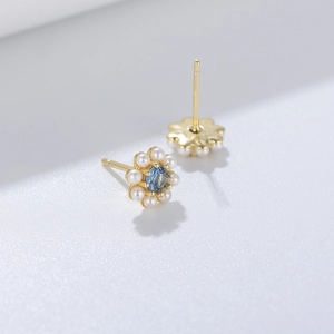 Close-up of flower stud earrings with white pearl petals and a blue zircon center