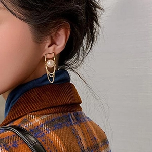 Close-up of gold tassel pearl earrings with cubic zirconia worn by a female model