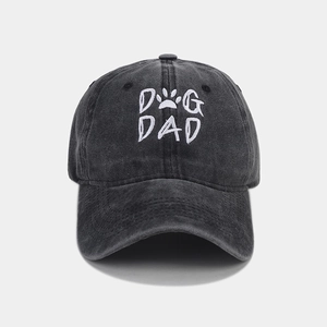 Close-up of white DOG DAD embroidery with paw print on washed dark grey cotton baseball cap
