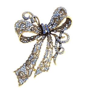 Vintage style bow brooch with light blue crystals and antique bronze finish on white